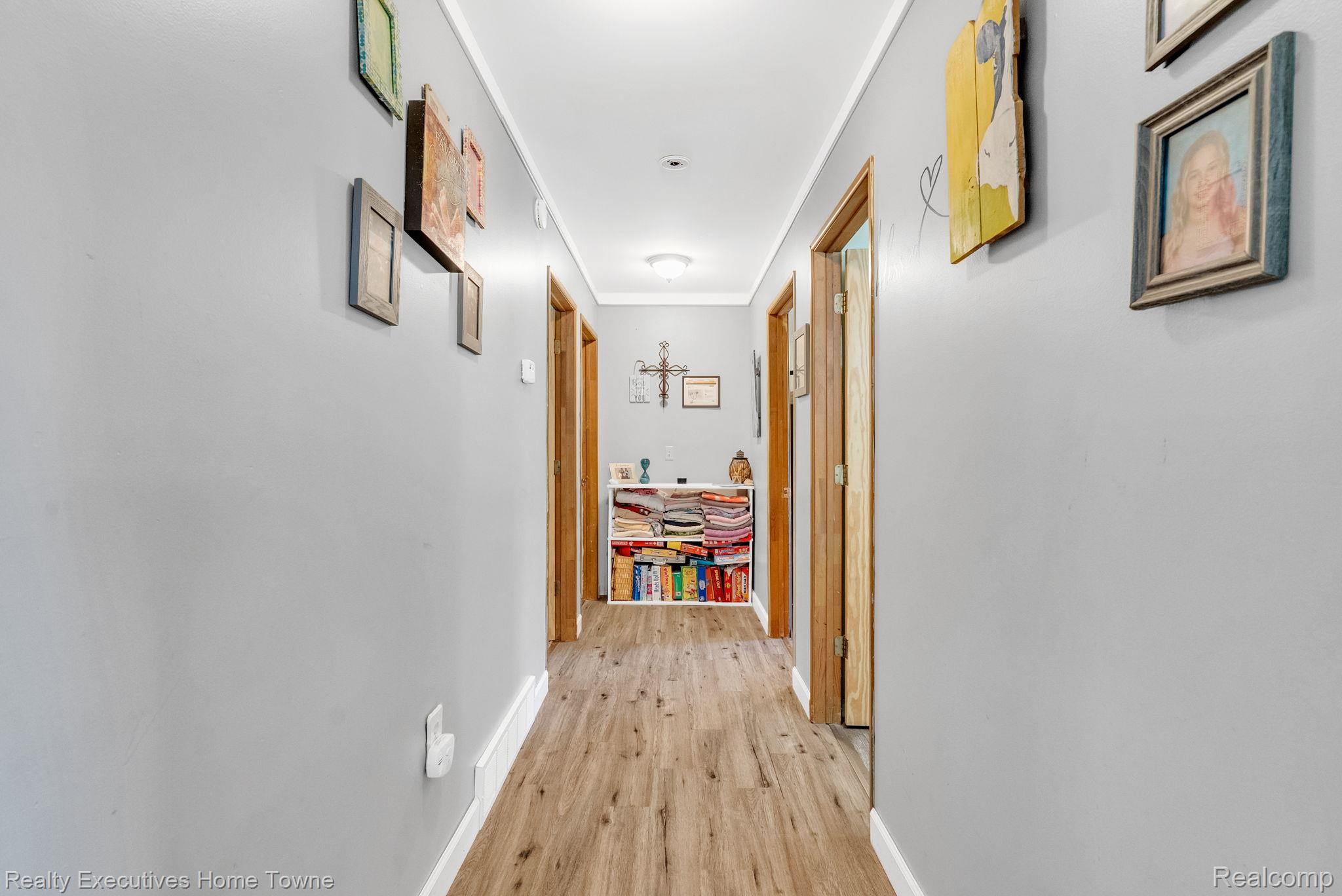 6560 Roach Road Lexington, MI 48450 - Photo 18 of 36 Hallway featuring wood-finish flooring, light gray walls, and white baseboards