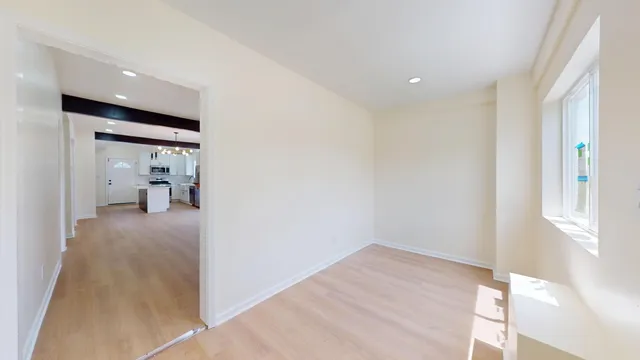 a view of a hallway with wooden floor and a bathroom
