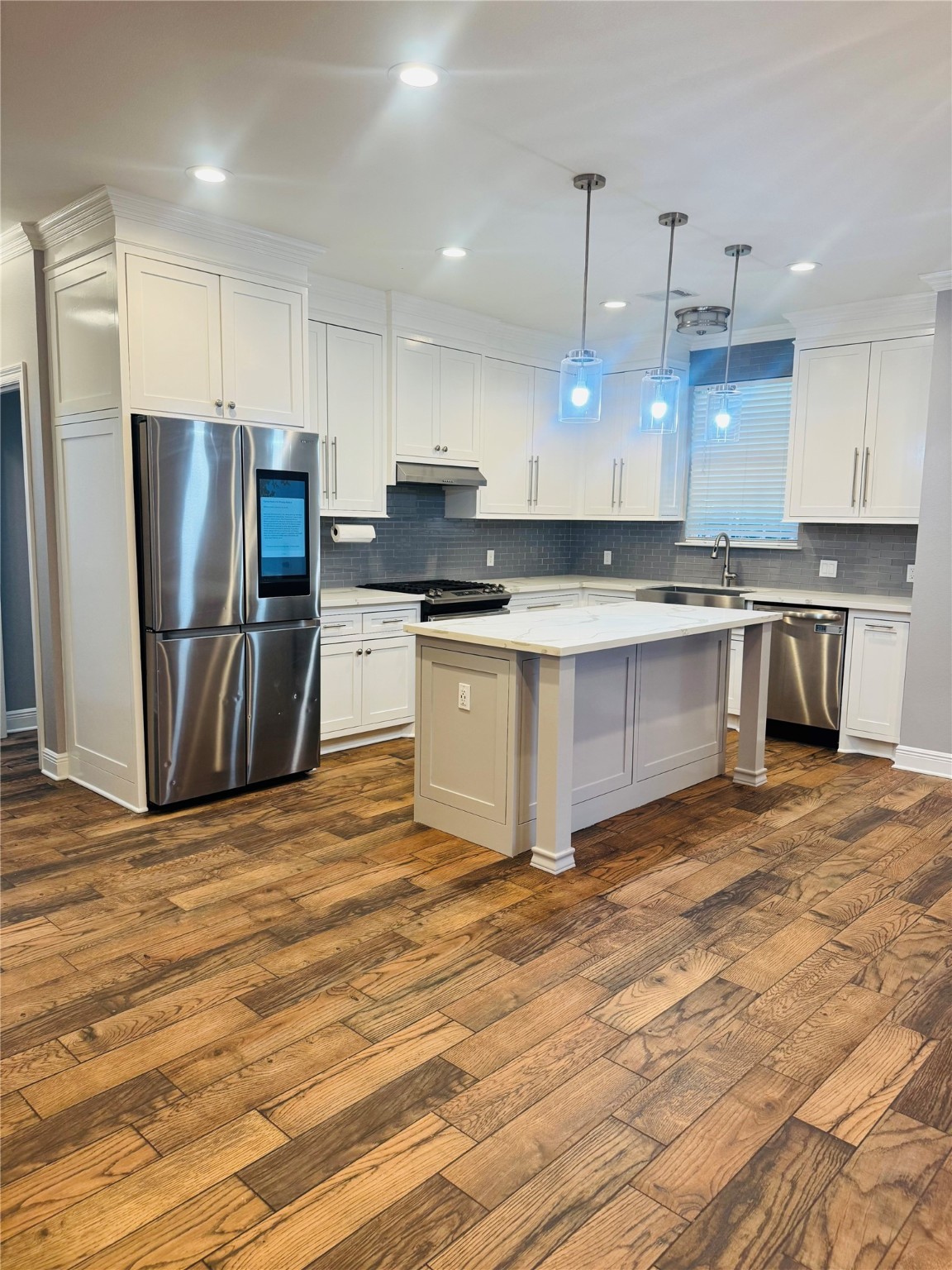 a kitchen with stainless steel appliances granite countertop a stove top oven a refrigerator and a sink