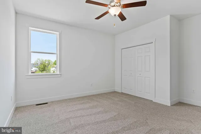 an empty room with a window and a fan