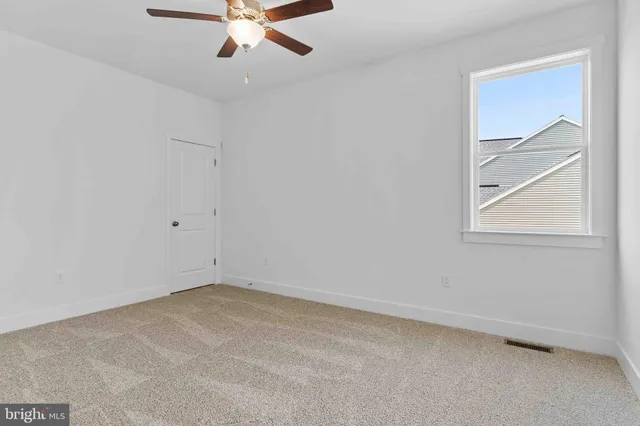 an empty room with a window and a ceiling fan