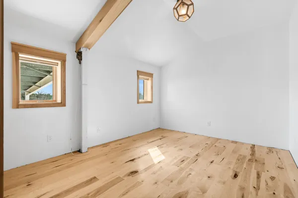 a view of empty room with wooden floor and window