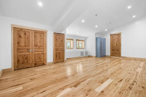 a view of an empty room with wooden floor and entryway