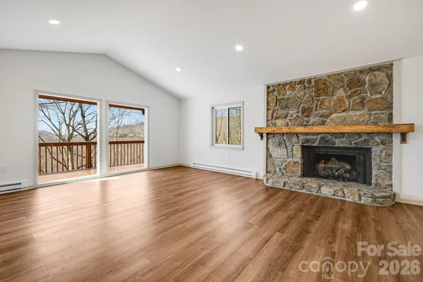 a view of an empty room with a window and wooden floor