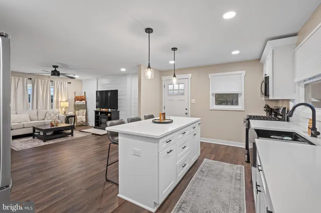 a kitchen with stainless steel appliances kitchen island granite countertop a sink stove and wooden floor