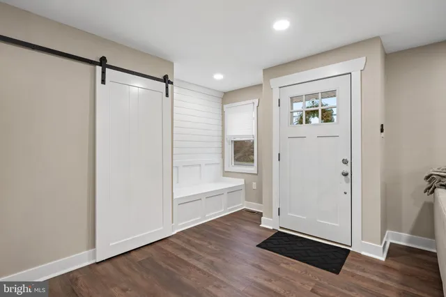 a view of an empty room with wooden floor and a bathroom