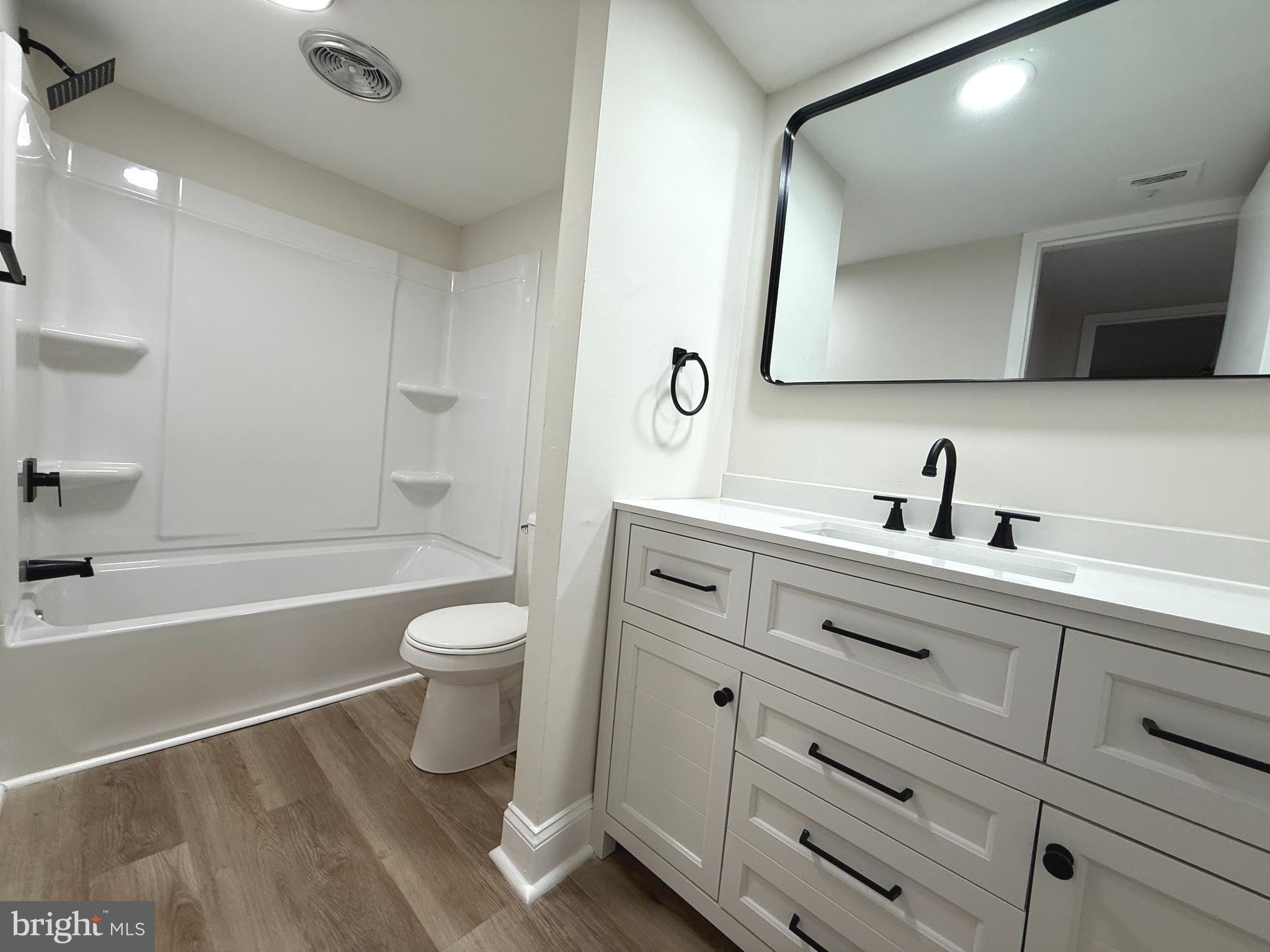 8689 Greenbelt Road, Unit 101 Greenbelt, MD 20770 - Photo 18 of 27 a bathroom with a toilet a sink a mirror and bathtub
