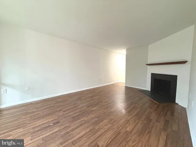 a view of empty room with wooden floor and fireplace