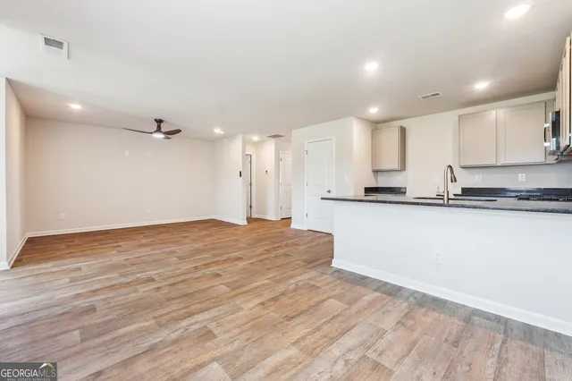 a view of a kitchen with kitchen island a sink wooden floor and stainless steel appliances