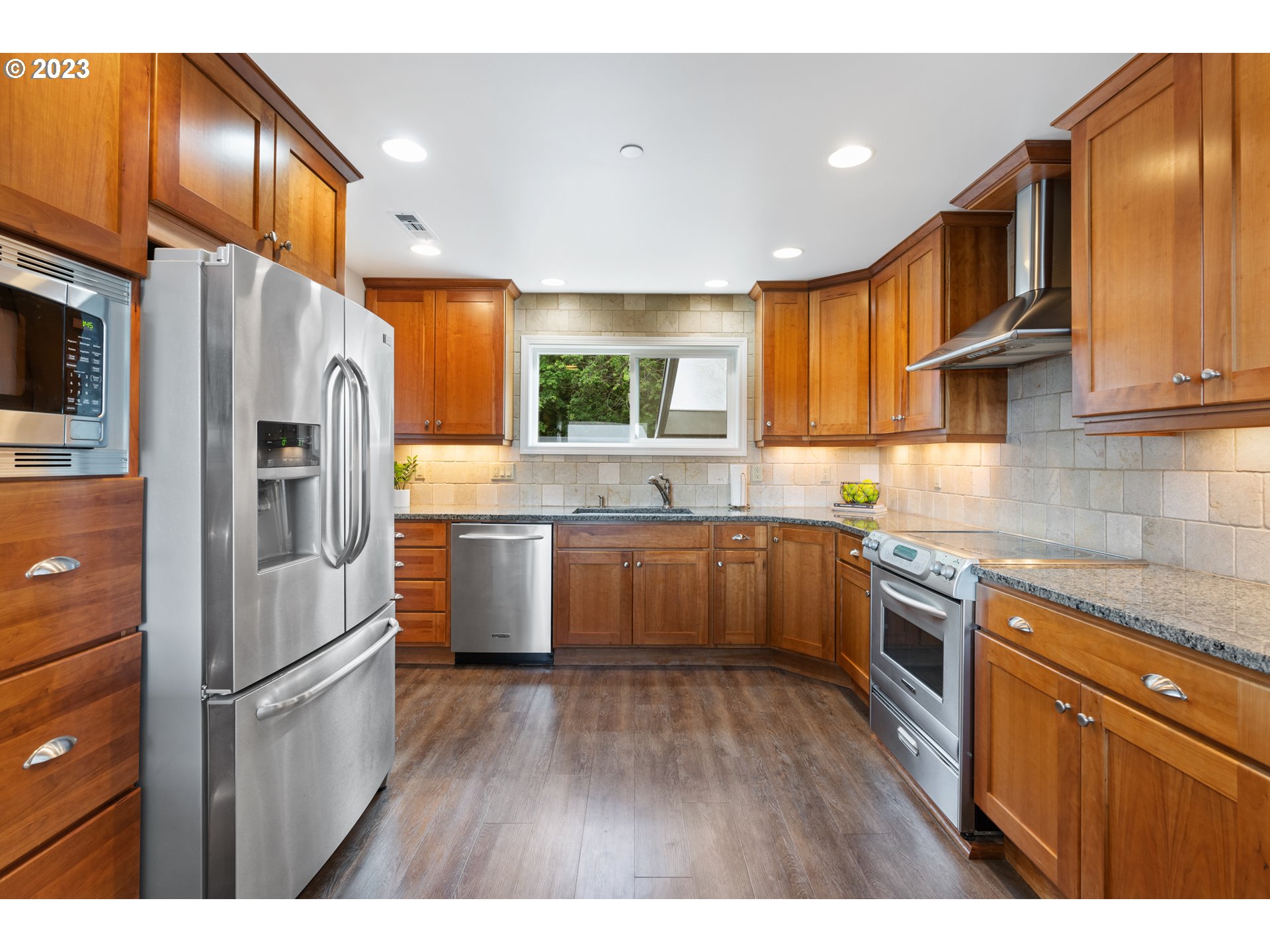 5411 Southwest View Point Terrace Portland, OR 97239 - Photo 10 of 44 a kitchen with stainless steel appliances granite countertop a refrigerator a sink dishwasher a stove with wooden cabinets and floor