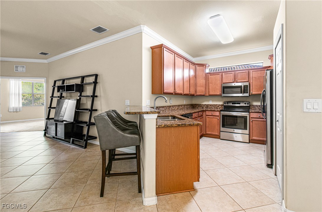 9101 Water Tupelo Road Fort Myers, FL 33912 - Photo 16 of 43 a kitchen with stainless steel appliances granite countertop a stove top oven a sink a dining table and chairs