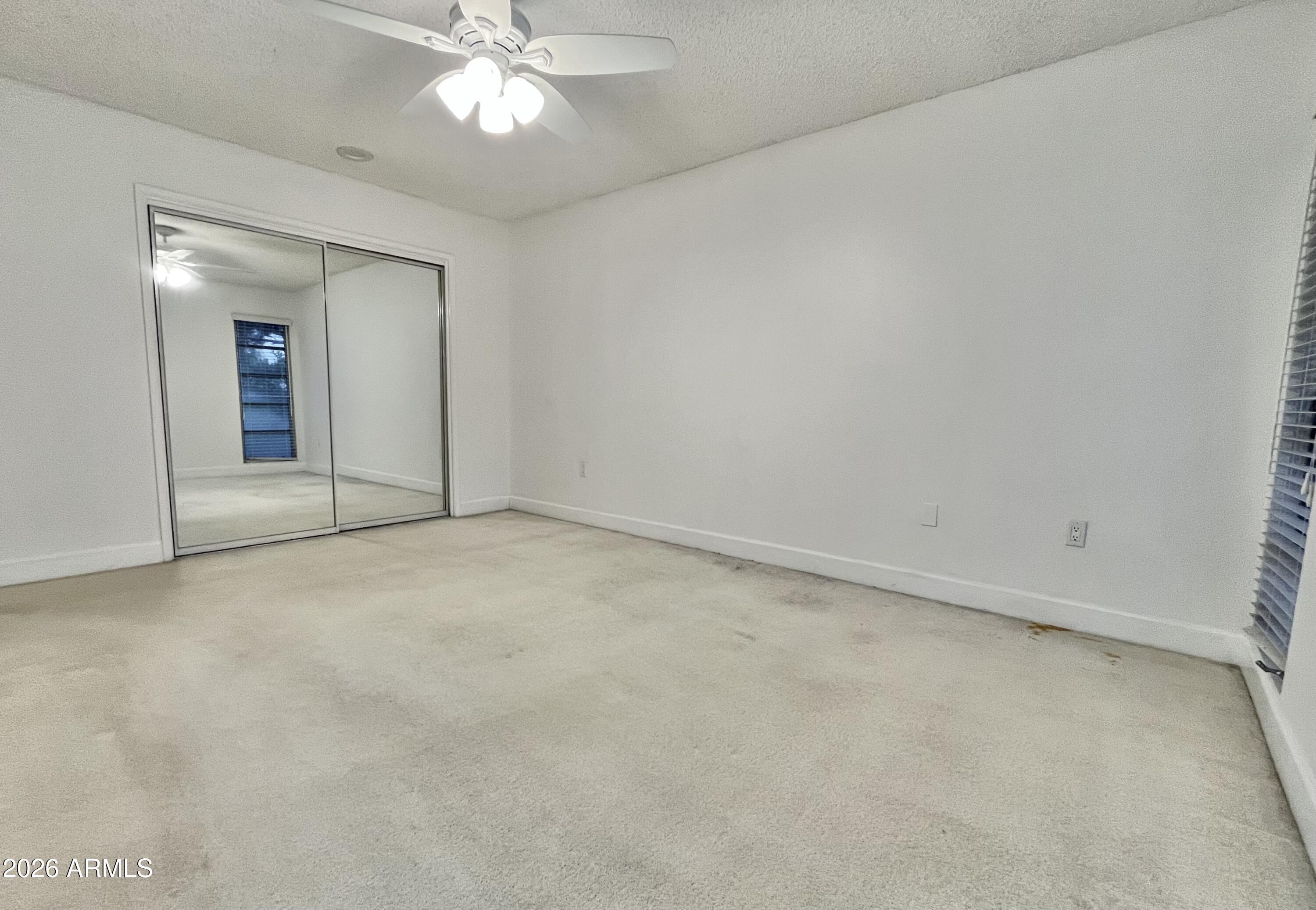9718 West Oak Ridge Drive Sun City, AZ 85351 - Photo 16 of 41 an empty room with a chandelier fan and windows