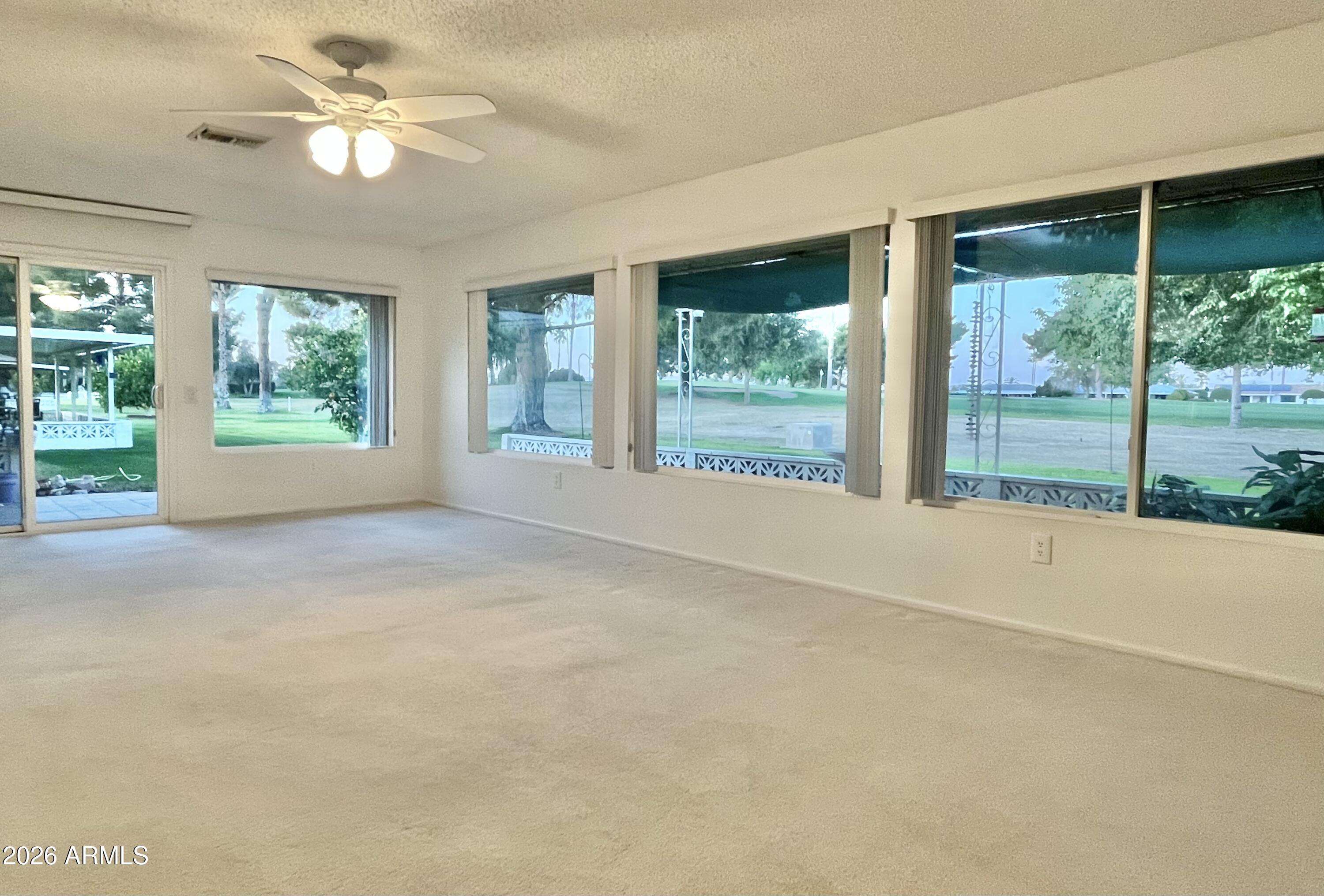 9718 West Oak Ridge Drive Sun City, AZ 85351 - Photo 3 of 41 a view of a room with a large window wooden floor and a ceiling fan