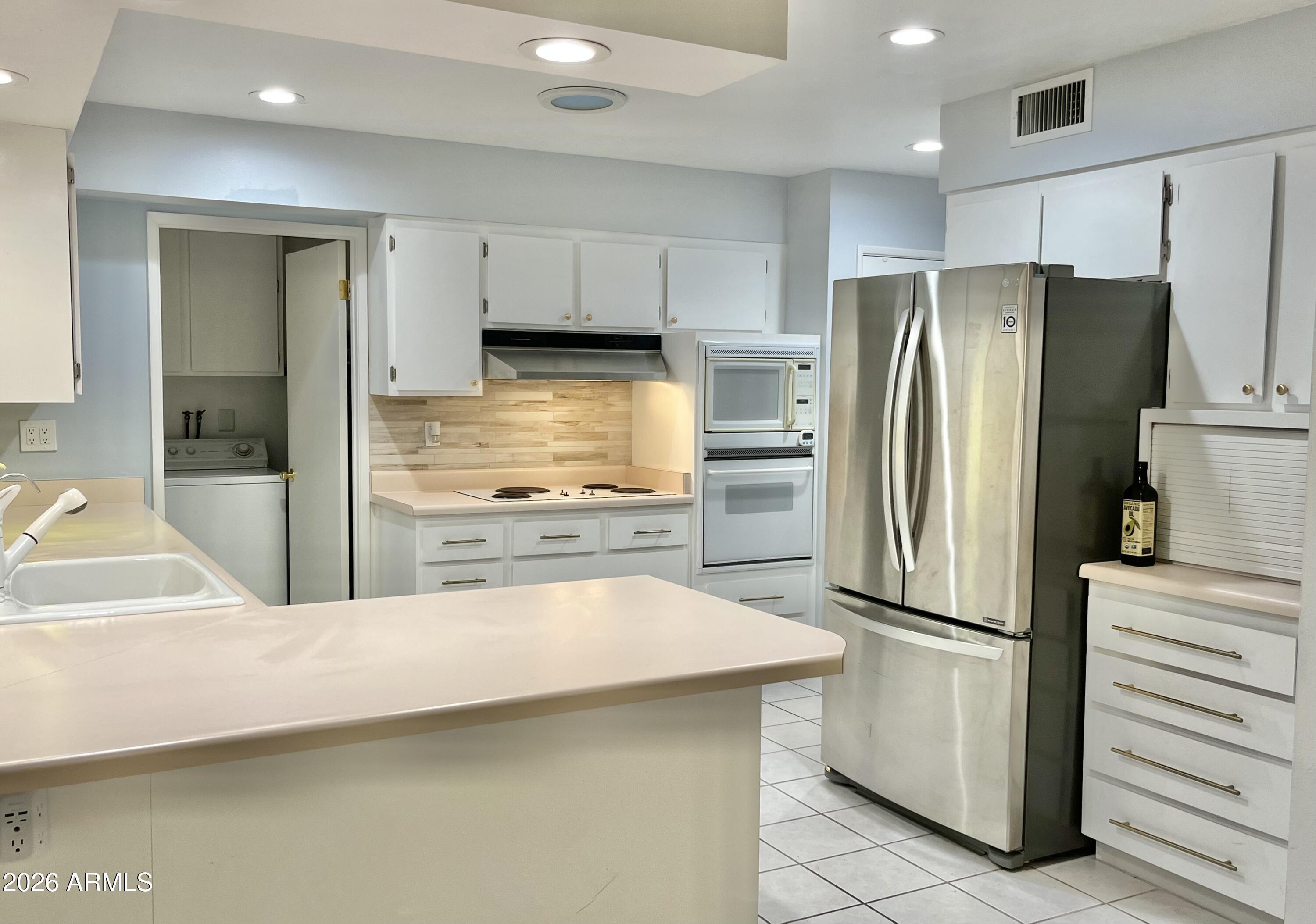 9718 West Oak Ridge Drive Sun City, AZ 85351 - Photo 4 of 41 a kitchen with white cabinets and stainless steel appliances
