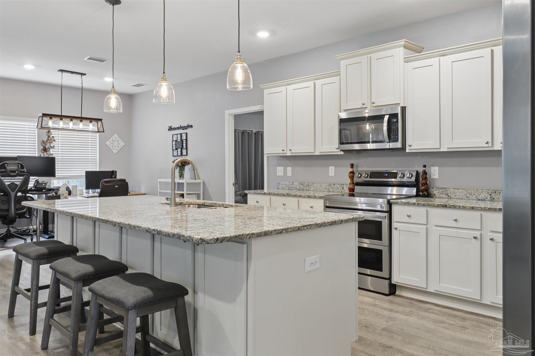 335 Cayden Way Cantonment, FL 32533 - Photo 17 of 30 a kitchen with stainless steel appliances granite countertop a sink a stove a refrigerator and island with wooden floor