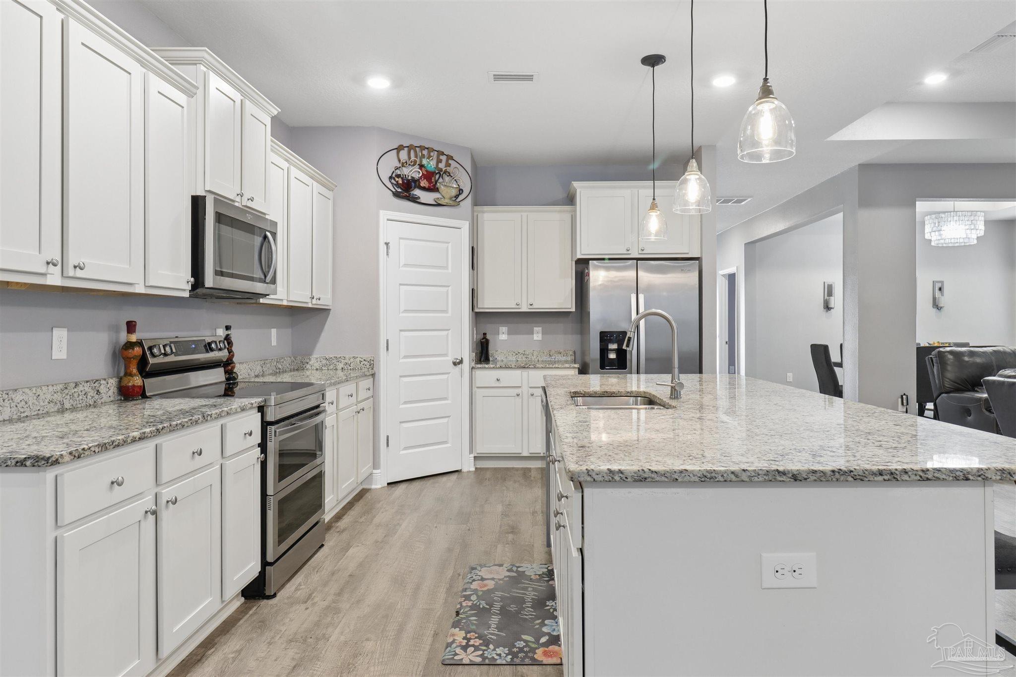 335 Cayden Way Cantonment, FL 32533 - Photo 18 of 30 a kitchen with stainless steel appliances granite countertop a sink a stove a refrigerator a center island and cabinets