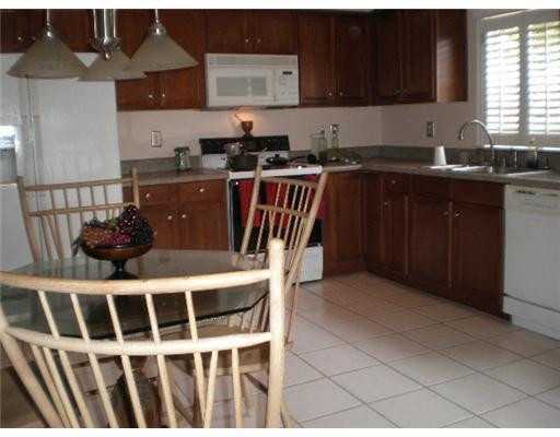 9727 Tavernier Drive Boca Raton, FL 33496 - Photo 12 of 16 a kitchen with stainless steel appliances a sink a stove a table and chairs