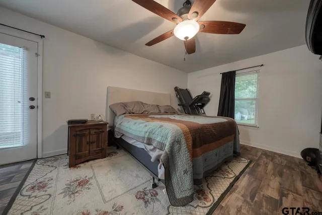 a bedroom with a bed and a dresser with wooden floor