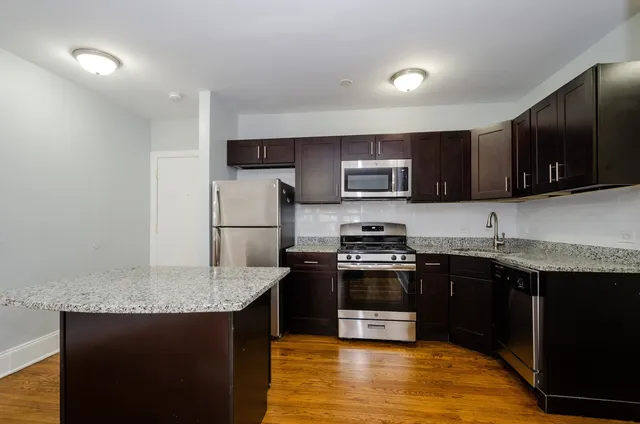 a kitchen with stainless steel appliances granite countertop a stove top oven a sink dishwasher and a microwave oven on the blue kitchen countertops