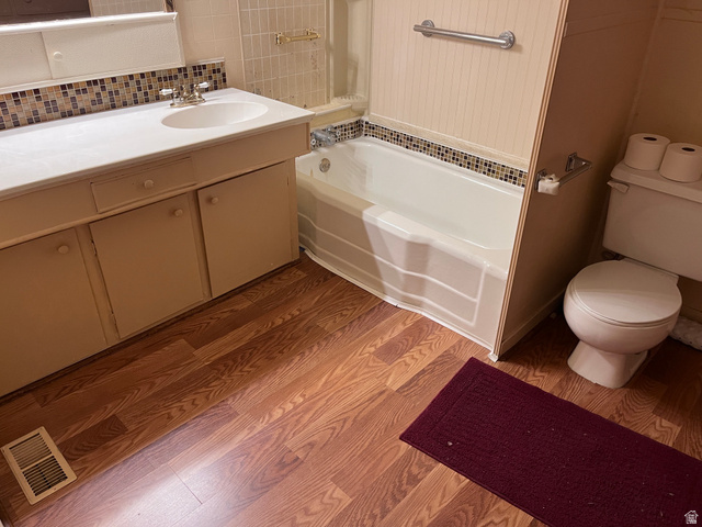 1766 Pine Rd Pine Canyon Tooele, UT 84074 - Photo 9 of 16 Bathroom featuring a white vanity with an integrated sink, a mosaic tile backsplash, and wood-finish flooring