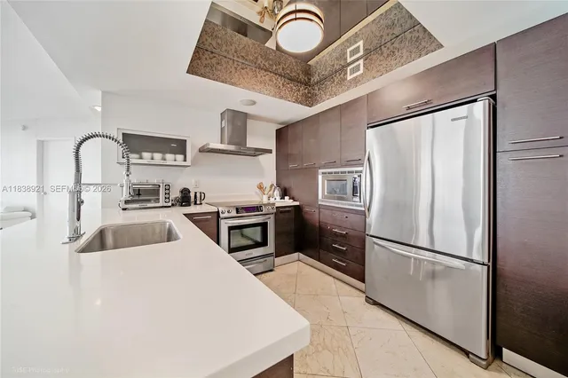 a kitchen with stainless steel appliances granite countertop a refrigerator a stove and a sink