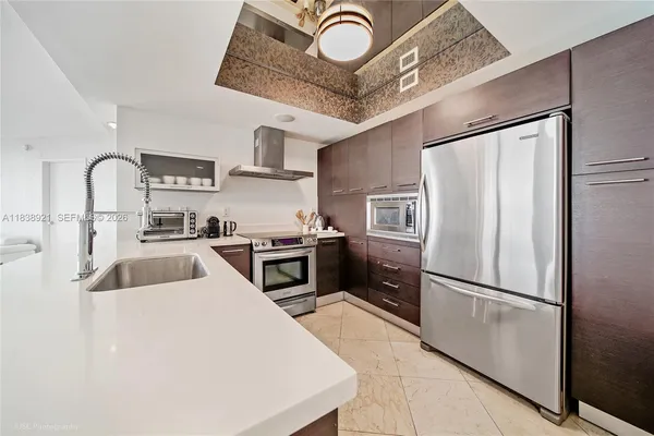 a kitchen with stainless steel appliances granite countertop a refrigerator a stove and a sink