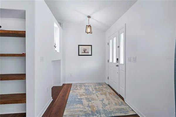 a view of a hallway with wooden floor and a bathroom