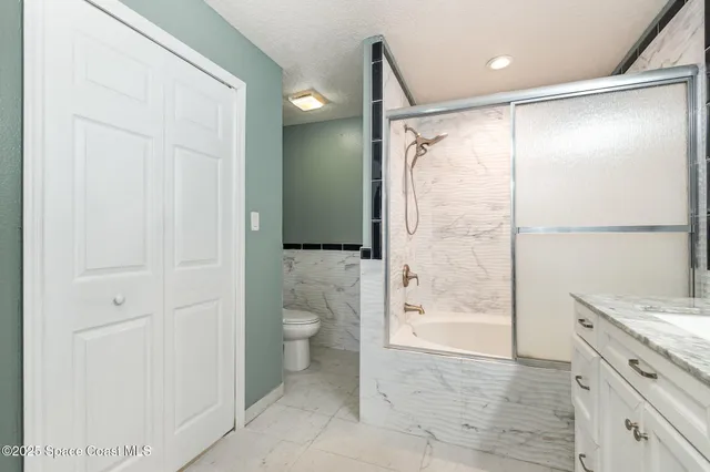 a bathroom with a granite countertop sink toilet and shower