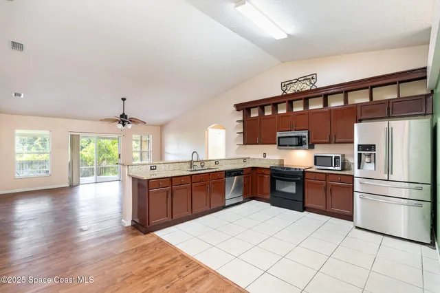 a kitchen with stainless steel appliances granite countertop a refrigerator a stove a sink dishwasher with a dining table and chairs