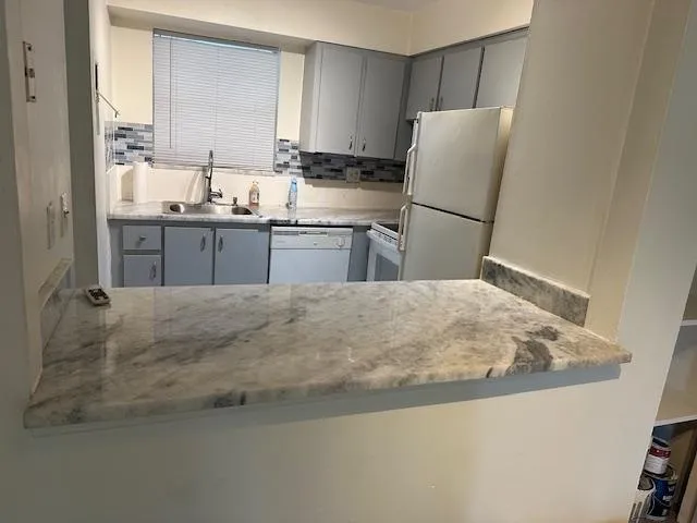 a kitchen with kitchen island a refrigerator stove and sink