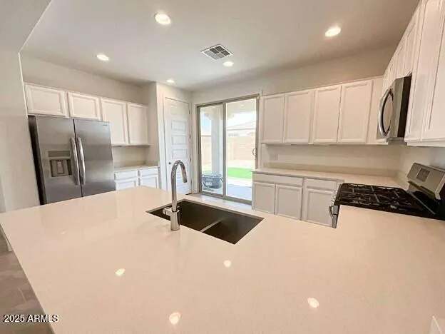 a kitchen with stainless steel appliances kitchen island a sink a stove a refrigerator and cabinets