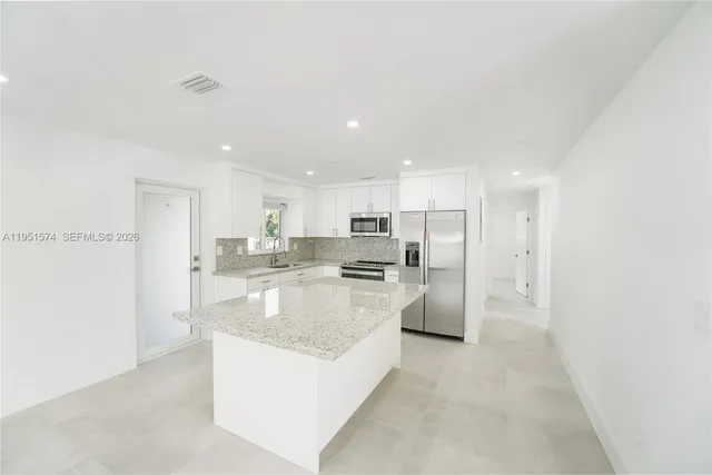 a large kitchen with kitchen island a refrigerator a stove a sink and a oven