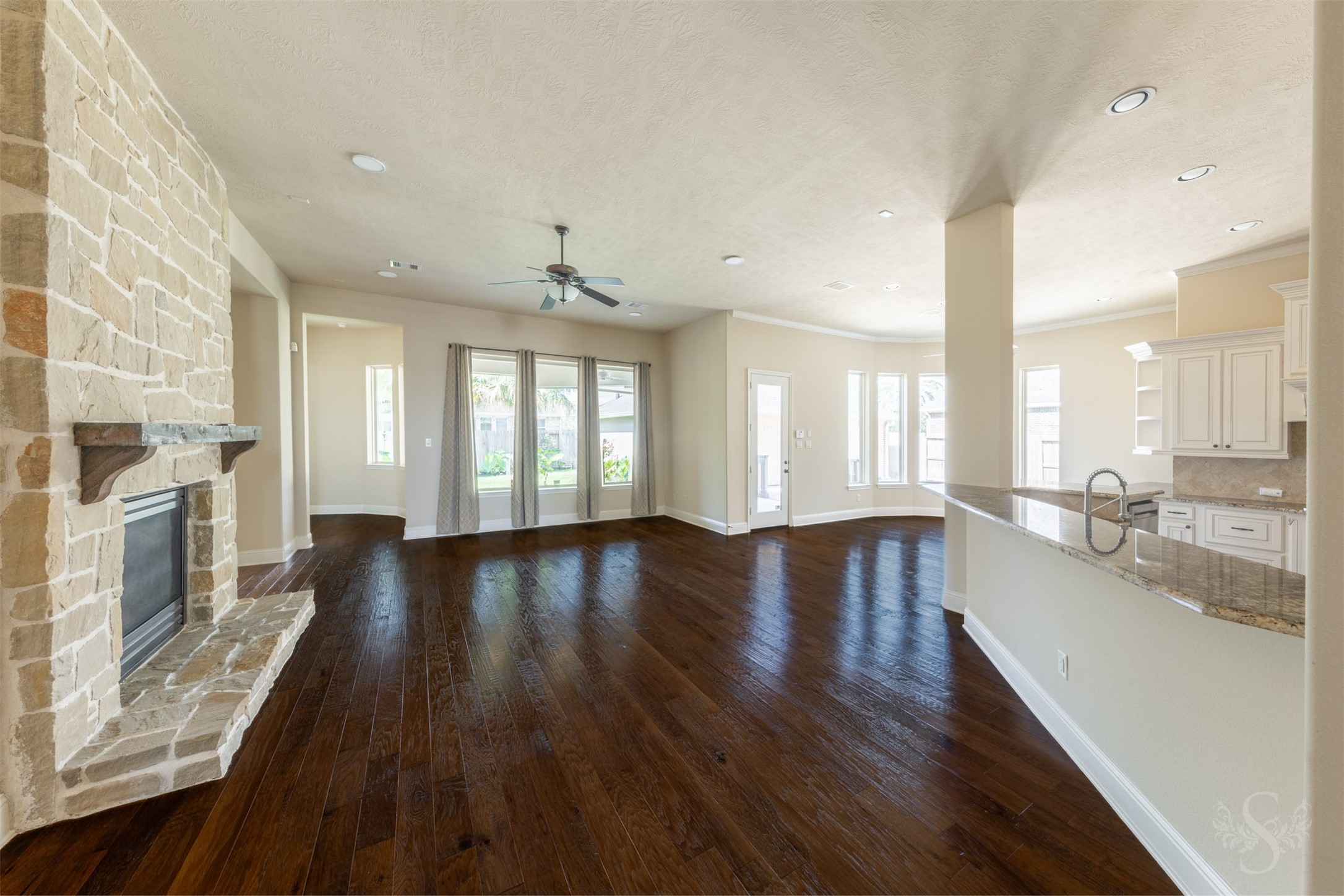 5803 Mustang Ridge Lane Fulshear, TX 77441 - Photo 3 of 48 Spacious family room features a striking floor-to-ceiling stone fireplace and an open-concept layout designed for gathering and entertaining. Walls of windows overlook the beautifully landscaped backyard and fill the space with natural light.