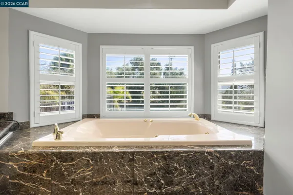 a bathroom with granite countertop bathtub and window