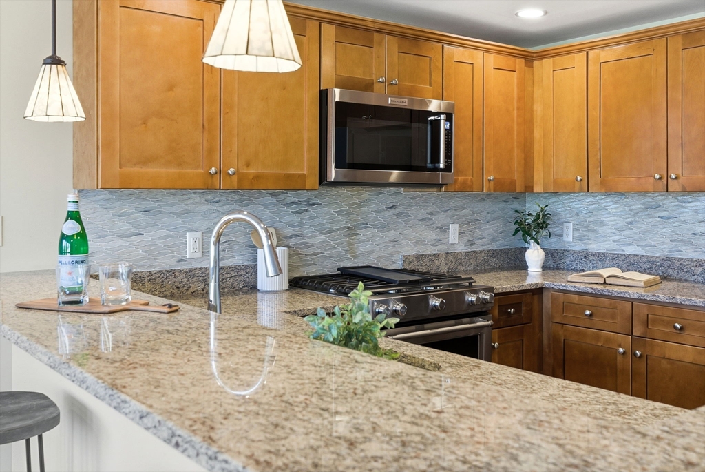 70 Great Road, Unit G Bedford, MA 01730 - Photo 4 of 15 a kitchen with stainless steel appliances granite countertop a sink a stove and a microwave