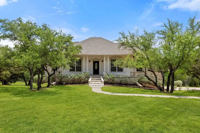 a front view of a house with a yard and trees