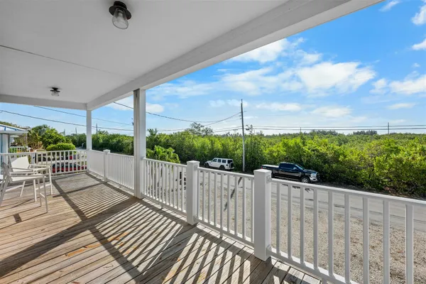 a view of a balcony with wooden floor & fence