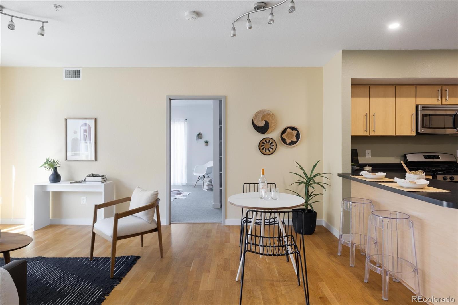 2999 Lawrence Street, Unit 202 Denver, CO 80205 - Photo 10 of 40 a kitchen with stainless steel appliances kitchen island granite countertop a stove a sink a dining table and chairs with wooden floor