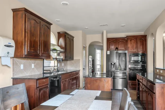 a large kitchen with stainless steel appliances granite countertop a stove refrigerator and cabinets