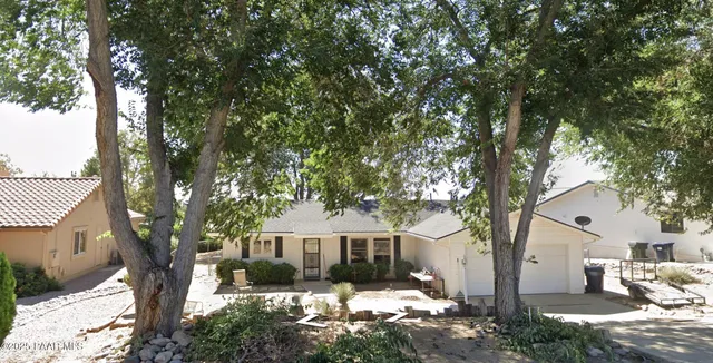 a front view of a house with a yard and large tree