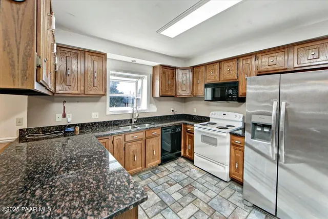 a kitchen with granite countertop a refrigerator stove top oven a sink and dishwasher