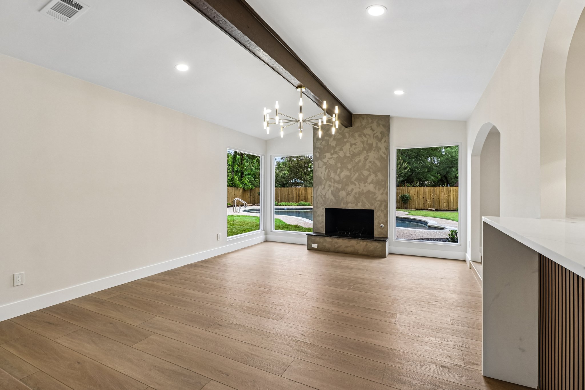 11809 Charing Cross Road Austin, TX 78759 - Photo 5 of 34 A spacious living area with hardwood floors, a modern fireplace, and large windows overlooks a private pool and yard.