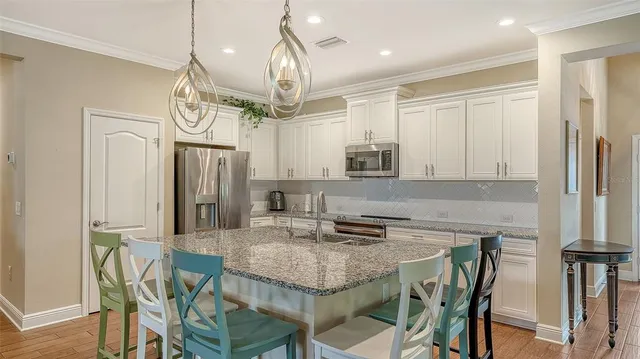 a kitchen with stainless steel appliances granite countertop a kitchen island a stove a table and chairs in it