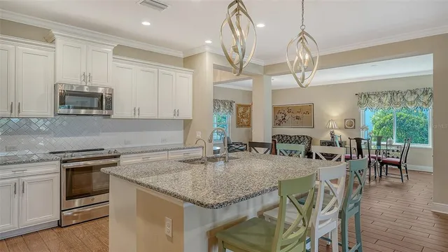 a kitchen with stainless steel appliances granite countertop a kitchen island hardwood floor sink stove dining table and chairs