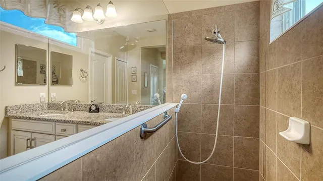 a bathroom with a granite countertop sink a mirror and a shower