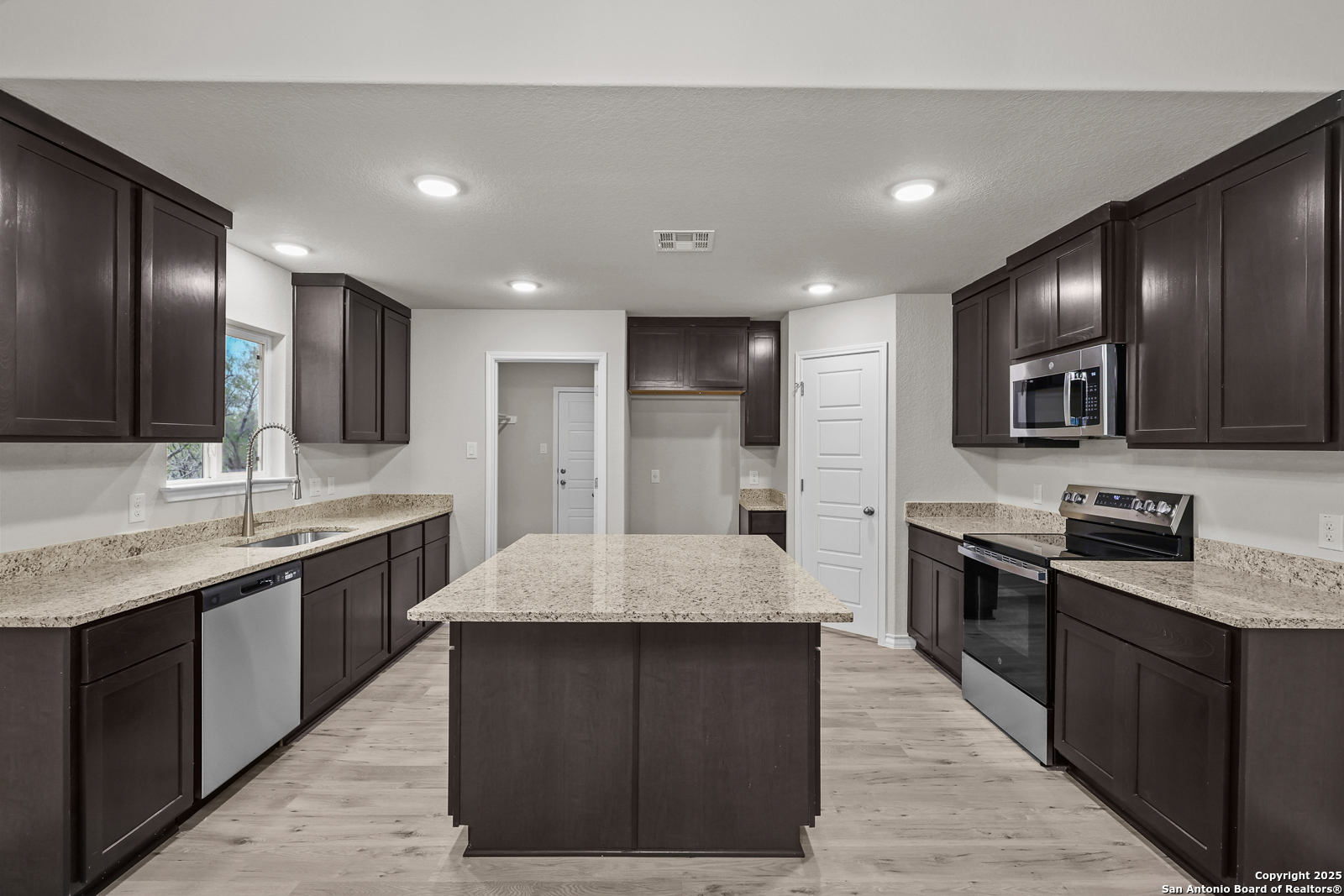 149 Sylas Hayes Loop Pleasanton, TX 78064 - Photo 12 of 38 a large kitchen with stainless steel appliances kitchen island granite countertop a stove and a sink