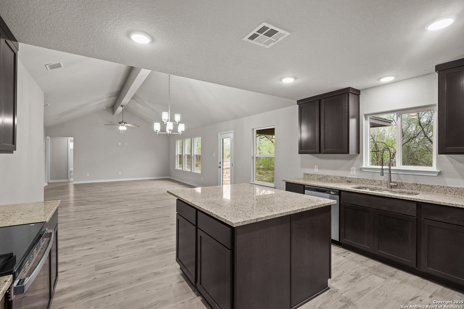149 Sylas Hayes Loop Pleasanton, TX 78064 - Photo 15 of 38 a kitchen with granite countertop cabinets a sink dishwasher and a large refrigerator with wooden floor