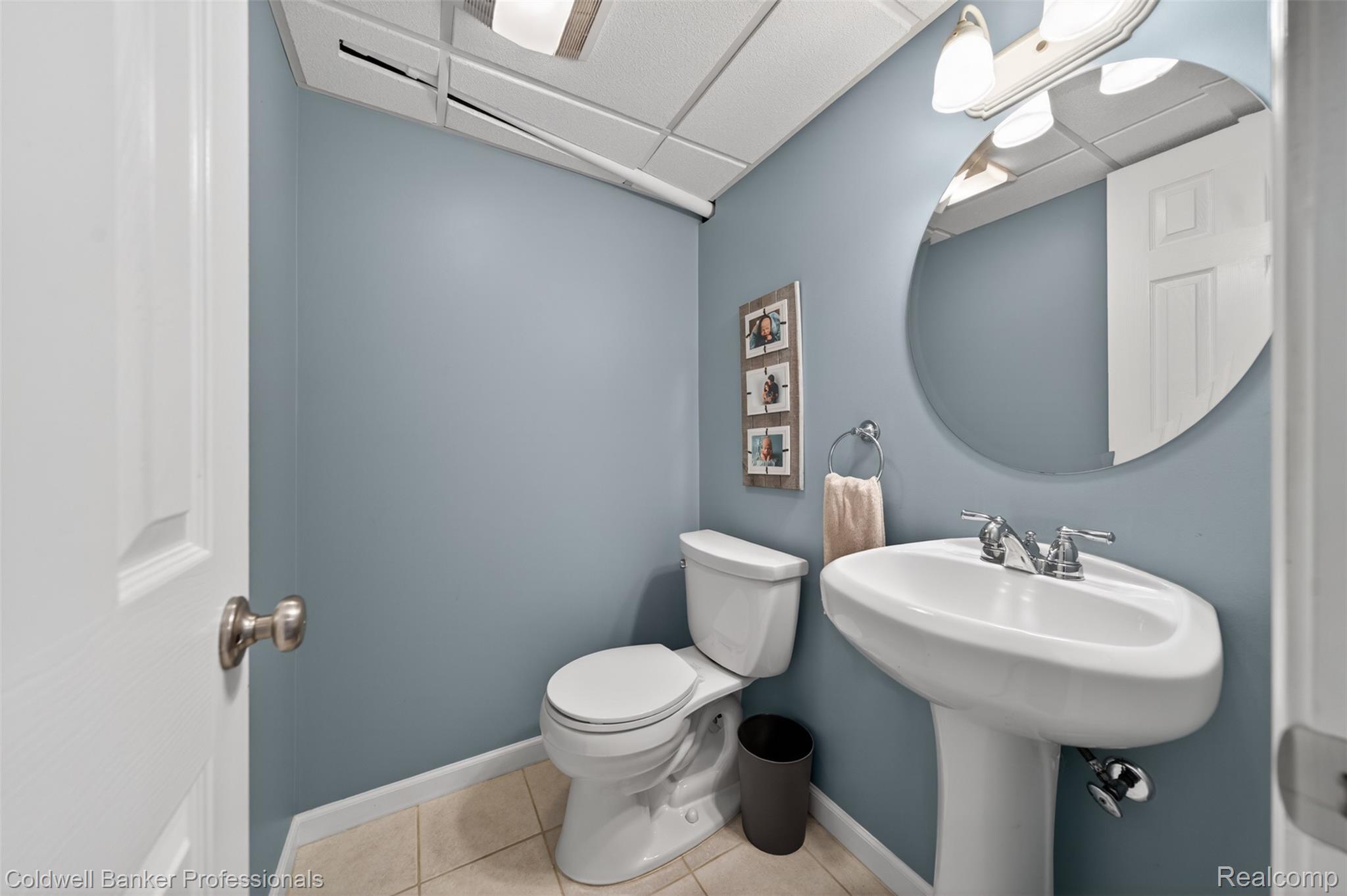 2666 Windemere Road Birmingham, MI 48009 - Photo 16 of 24 Pedestal sink with chrome faucet, circular mirror, and white toilet