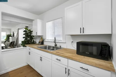 a kitchen with white cabinets and a stove with wooden floor