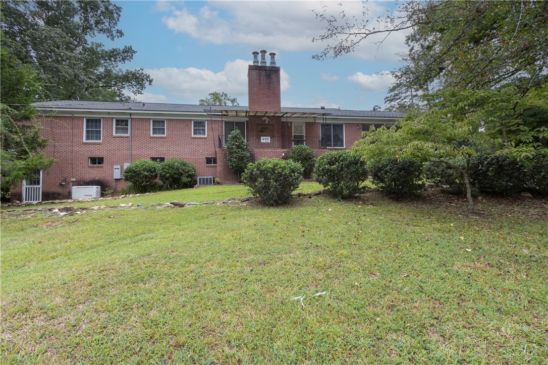 118 Blair Road Belton, SC 29627 - Photo 46 of 49 Mature trees and a gentle grassy slope frame the rear brick exterior.